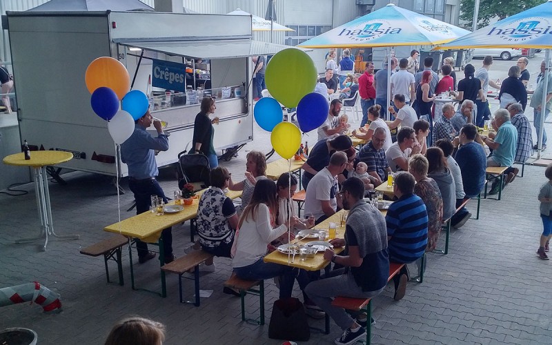 Münch+Münch Familiensommerfest - Belegschaft an Tischen und Bänken im Hof